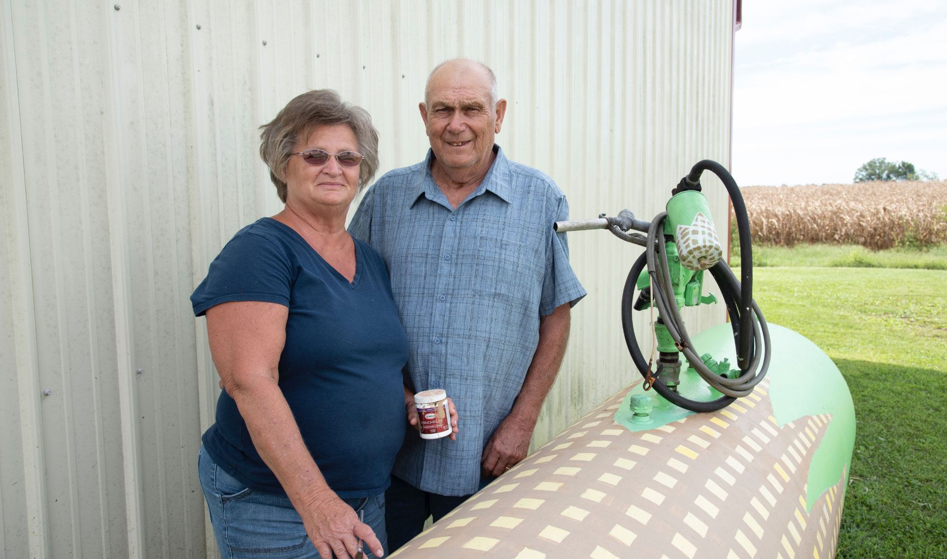 Charlotte and her husband pose together for a photo outside of their barn.