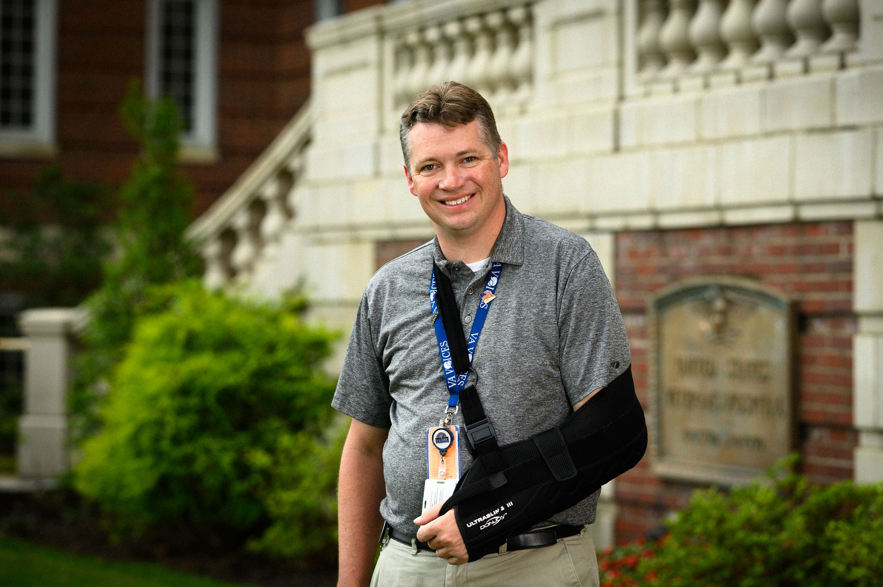 Leonard wears a black sling to support his arm and shoulder, but still smiles.